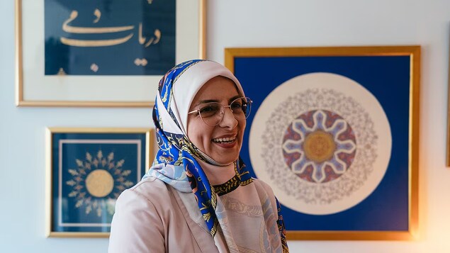 المُذهِّبة الكندية الإيرانية مريم نديمي تقف أمام بعضٍ من لوحاتها.