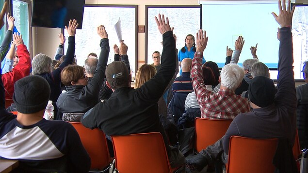 Une vingtaine de personnes assises sur leur chaise passent au vote en levant le bras. Une vingtaine de personnes assises sur leur chaise passent au vote en levant le bras.