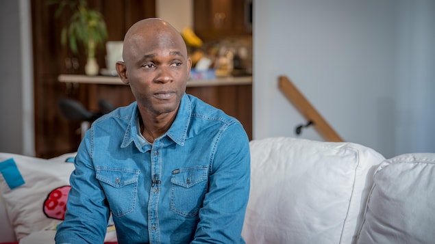 Assim Traoré est assis sur un sofa dans son salon.