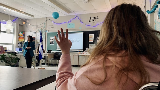 Sonia LeBel est debout à l’avant d’une classe devant des élèves de dos qui sont assis.