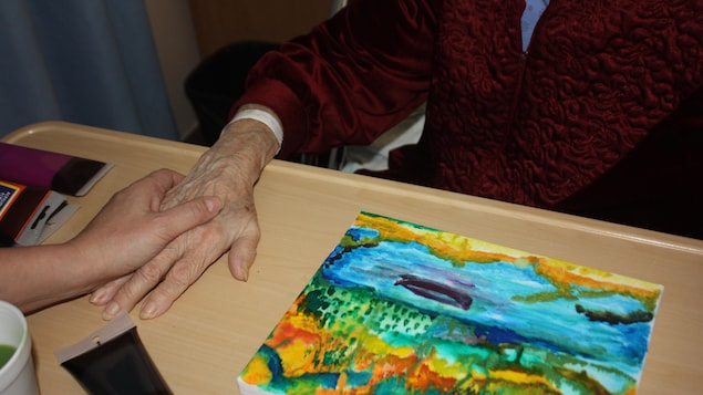 Une dame âgée et son oeuvre, une toile colorée.