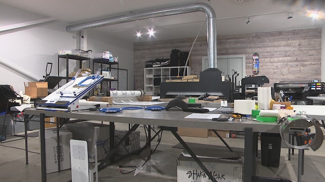 Une grande table se trouve au centre d’un atelier de travail.