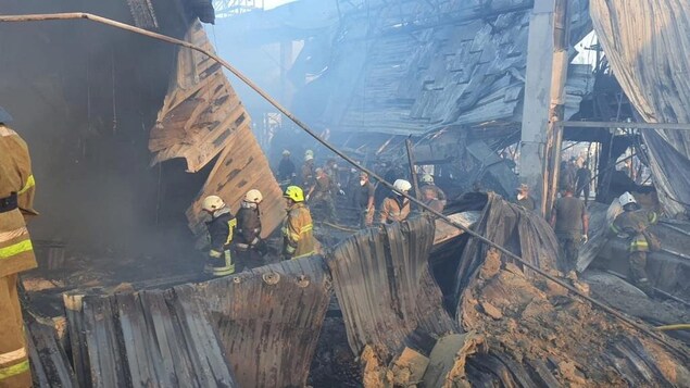 Des pompiers au milieu d'un immeuble détruit. 