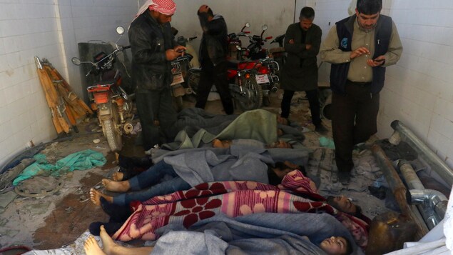 Des hommes se tiennent près des corps de victimes de l’attaque au gaz dans la ville de Khan Sheikhoun, en Syrie, le 4 avril 2017.