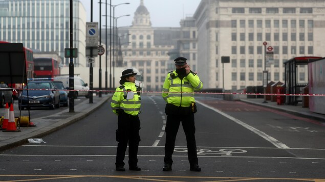 Deux policiers bloquent le passage menant au London Bridge.