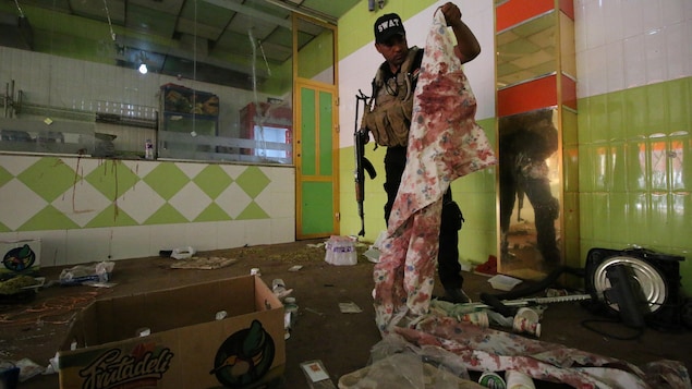 Un membre des forces irakiennes tient dans ses mains un bout de tissu ensanglanté dans un restaurant qui a été la cible d'une attaque à Nassiriya, en Irak. Un membre des forces irakiennes tient dans ses mains un bout de tissu ensanglanté dans un restaurant qui a été la cible d'une attaque à Nassiriya, en Irak.