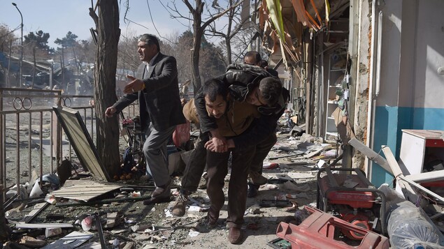 Un bénévole afghan transporte le corps d’une personne qui a été blessée lors de l’explosion d’une bombe à Kaboul, le 27 janvier 2018. L’attentat, revendiqué par les talibans, a tué au moins 17 personnes et en blessées 110 autres.