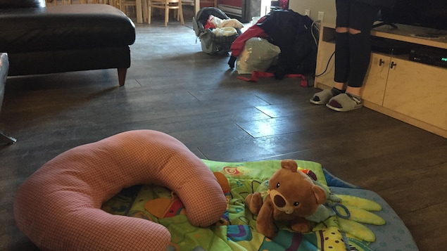 Des jouets, un siège pour bébé, des sacs dans une pièce commune