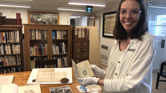 Audrey Julien, archiviste responsable au Centre d'archives du Monastère des Augustines, tient un livre ancien.