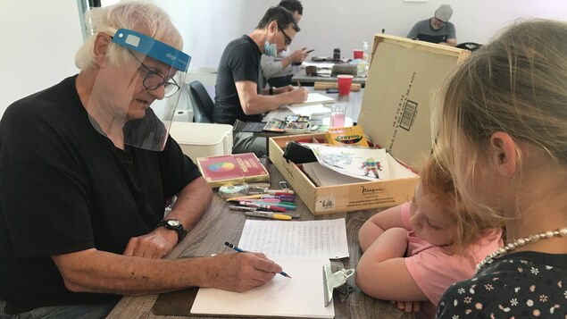 Un illustrateur dessine devant deux jeunes filles.