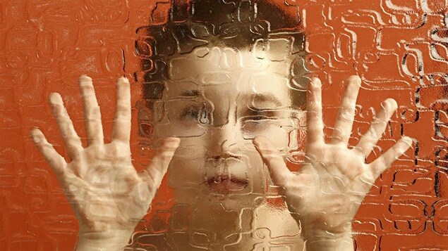 Un enfant prisonnier derrière une paroi translucide.