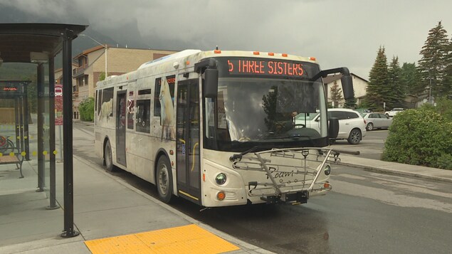 Un autobus de Roam Transit passe devant un abri-bus sous un ciel orageux.