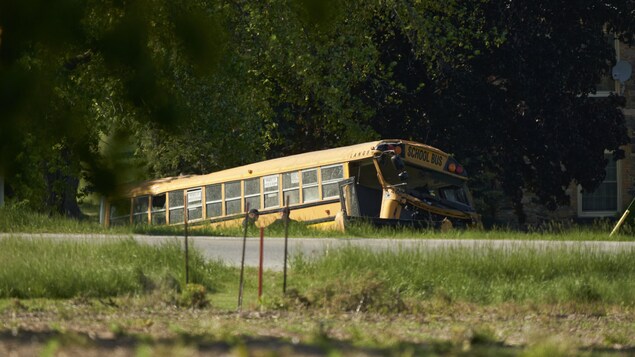 Un autobus scolaire accidenté au bord de la route après une collision.