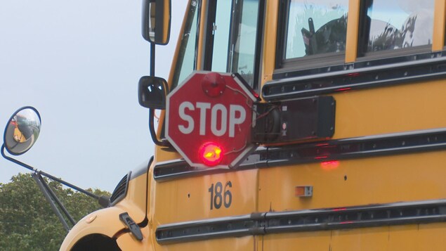 Un autobus scolaire a déployé son panneau d'arrêt destiné aux automobilistes. Un autobus scolaire a déployé son panneau d'arrêt destiné aux automobilistes.