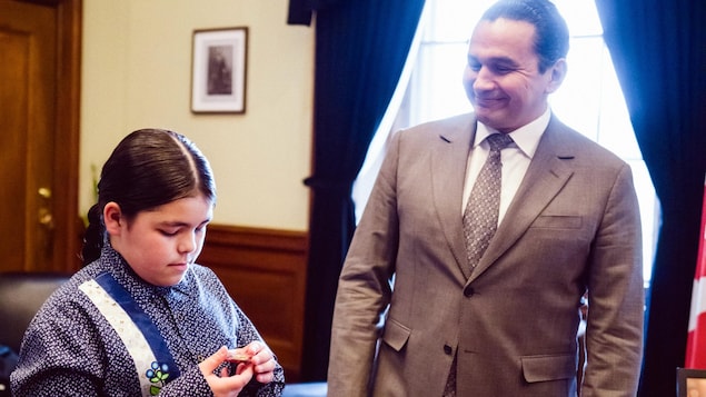 Le jeune Theo Osborne regardant une pièce de jeu avec le premier ministre du Manitoba, Wab Kinew, dans son bureau.