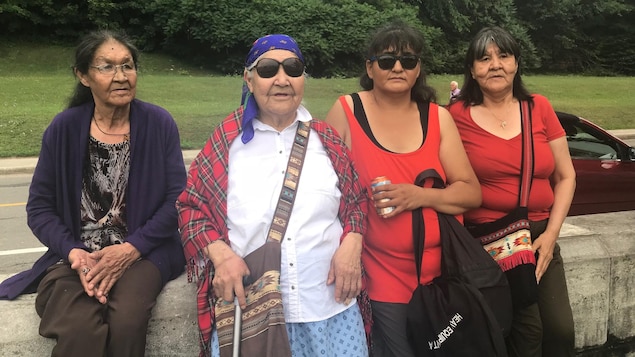 Quatre femmes autochtones sont assises sur un muret près de la basilique de Sainte-Anne-de-Beaupré.