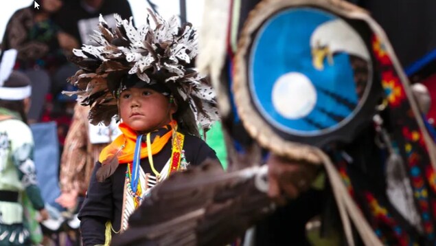 Un enfant porte un habit traditionnel autochtone.