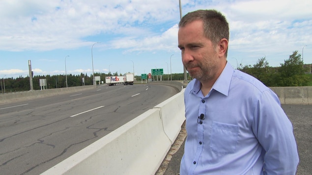 Un homme en entrevue en bordure d'une autoroute. Un homme en entrevue en bordure d'une autoroute.