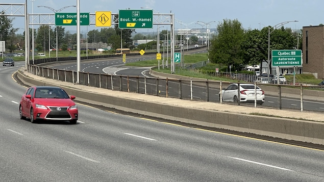 Deux voitures en train de circuler sur l'autoroute Laurentienne en été.