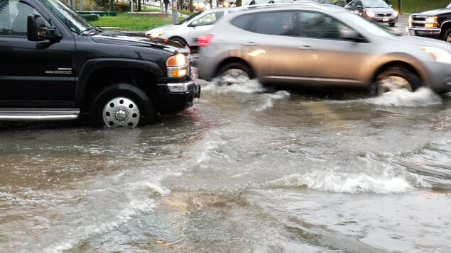 Plusieurs voitures qui roulent dans les rues inondées Plusieurs voitures qui roulent dans les rues inondées
