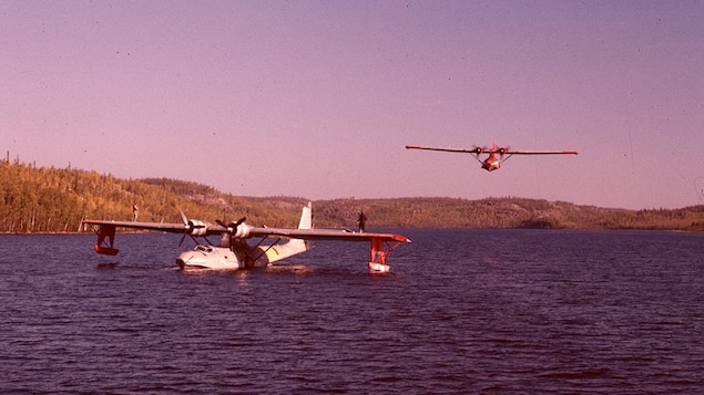 Un avion sur un lac et un autre en vol à basse altitude.