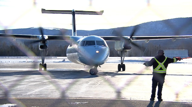 Un agent de piste fait circuler un avion sur la piste de l'aéroport de Gaspé.