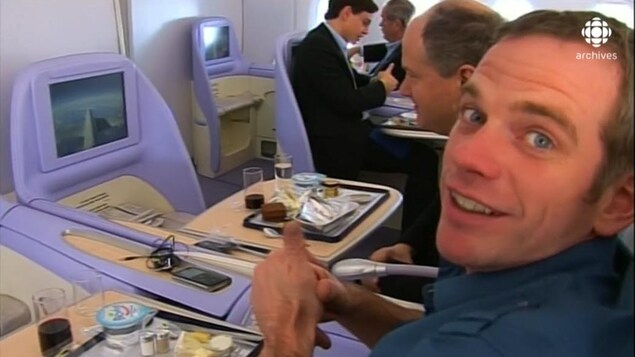 Le chanteur Garou, souriant, assis dans son siège d'avion avec écran montrant le ciel en vol. Le chanteur Garou, souriant, assis dans son siège d'avion avec écran montrant le ciel en vol.