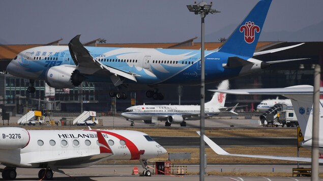 Un appareil en vol et trois autres sur les voies d'accès d'un aéroport.