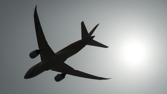 The silhouette of a plane in a sunny sky.