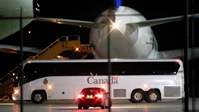 Un autobus attend des passagers qui sortent d'un avion.