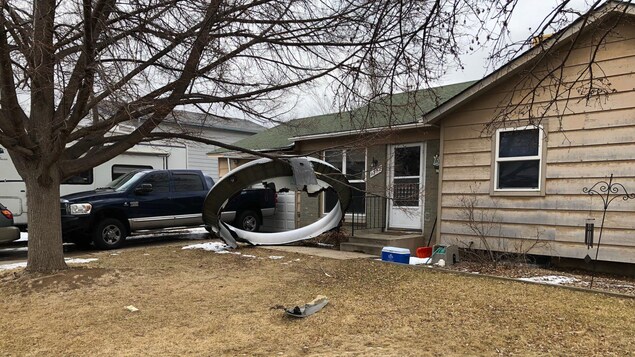 Un gros débris d'avion devant une maison