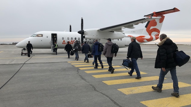 Des travailleurs se dirigent vers l'avion de la compagnie Air Inuit sur la piste de l'aéroport de Mont-Joli. 