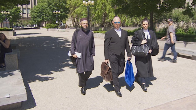 Omar Kalair et ses avocats, dont Edward Prutschi au centre, marchent dans la rue.