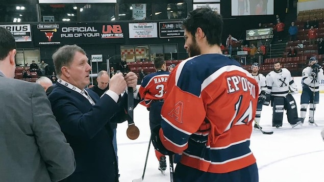 Un dignitaire accroche une médaille au cou d'un hockeyeur Un dignitaire accroche une médaille au cou d'un hockeyeur