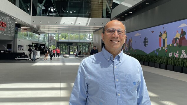A smiling man wearing a blue shirt poses in the Radio-Canada atrium.