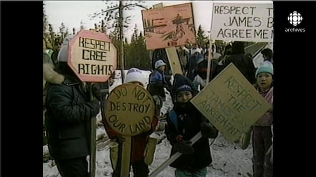 Enfants autochtones brandissant des pancartes avec les inscriptions «Respect the James Bay agreement» et «Do not destroy our land», en hiver