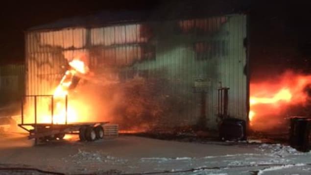 Des flammes sortent par les portes de l'usine en pleine nui Des flammes sortent par les portes de l'usine en pleine nui