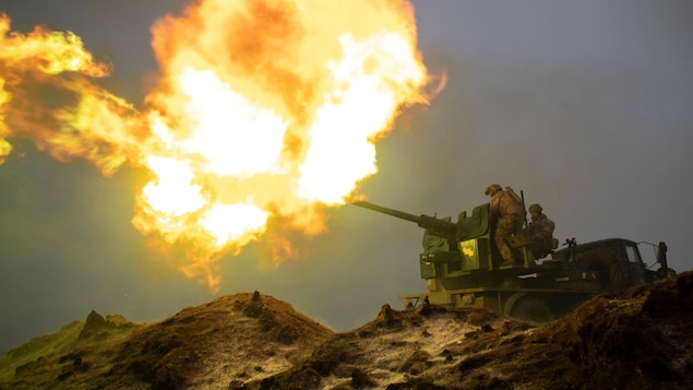 Una bola de fuego sale del cañón de un tanque con dos soldados encima.