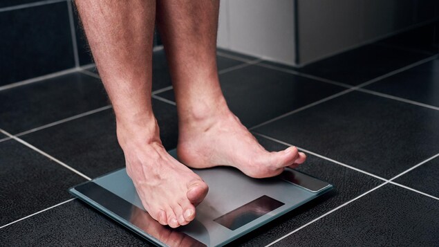 Un homme se tient sur une balance.