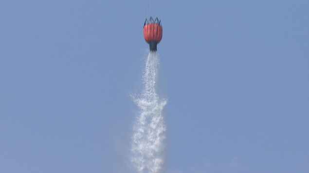 Un ballon transporté par un hélicoptère lâche son eau sur un feu de forêt Un ballon transporté par un hélicoptère lâche son eau sur un feu de forêt