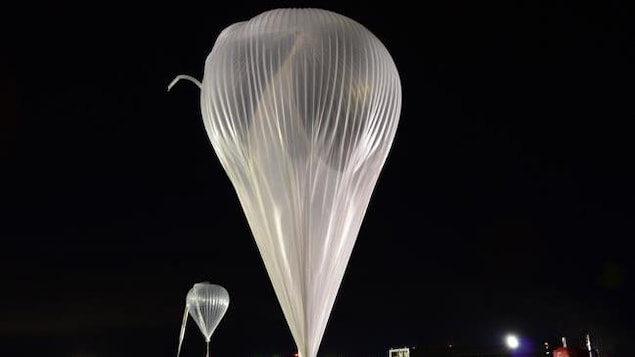 Deux ballons gonflables blanc, des ballons de scientifiques, de nuit, sur une piste d'atterrissage.
