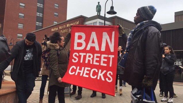 Des manifestants exhibent une bannière « Ban Street Checks » le 30 mars 2019 devant une bibliothèque d'Halifax.