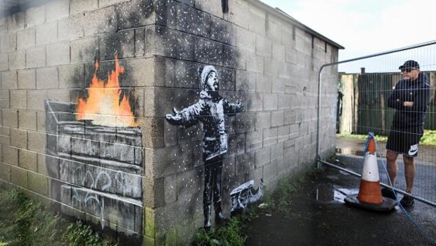 Un jeune garçon a les bras ouverts et respire des cendres d'un feu dans un conteneur.