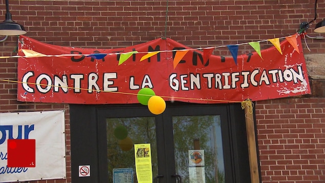 Une bannière au-dessus d'une porte, sur laquelle il est écrit : « Contre la gentrification ».