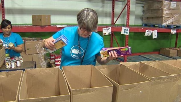 Une bénévole remplit des cartons de denrées à la banque alimentaire d'Edmonton.