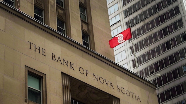 Façade extérieure de la Banque Scotia en pierres, un drapeau rouge de la banque flottant devant l'édifice. Façade extérieure de la Banque Scotia en pierres, un drapeau rouge de la banque flottant devant l'édifice.