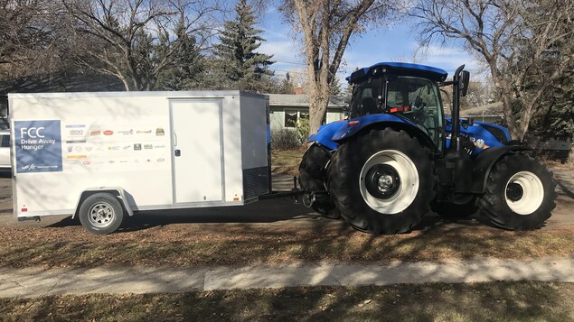 Un tracteur bleu qui tire une remorque où les sacs de nourriture sont entreposés. Un tracteur bleu qui tire une remorque où les sacs de nourriture sont entreposés.