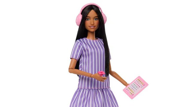 Une barbie autiste tient une tablette, un jouet fidget et porte des écouteurs.