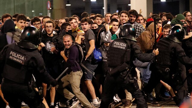 Des manifestants affrontent des policiers qui brandissent des matraques.