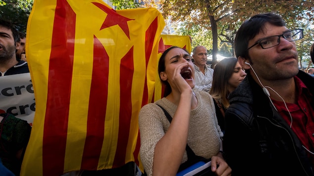 Une manifestante devant un drapeau indépendantiste catalan crie des slogans dans les rues de Barcelone.